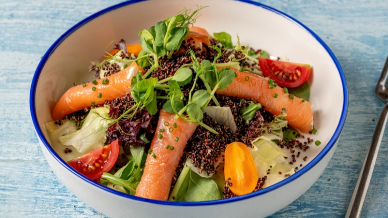 Salata sa lososom, povrćem i semenkama u tanjiru na stolu
