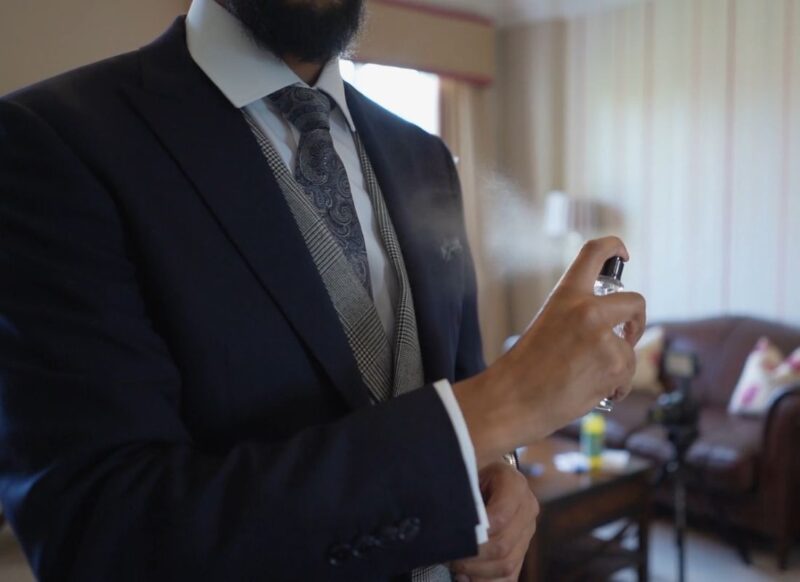 prikaz čoveka u odelu koji prska parfem na sebe