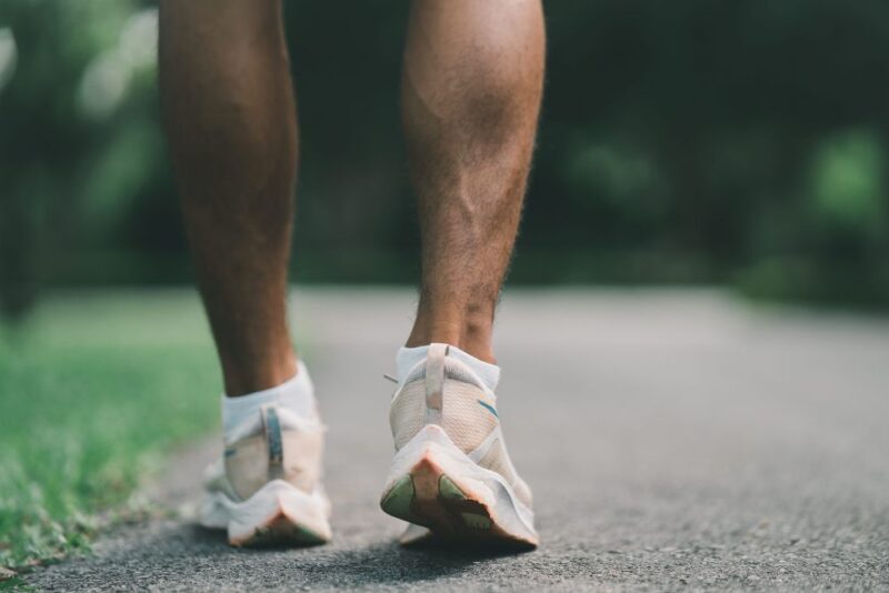 Osoba u sportskim patikama šeta stazom u prirodi radi očuvanja opšteg zdravlja.